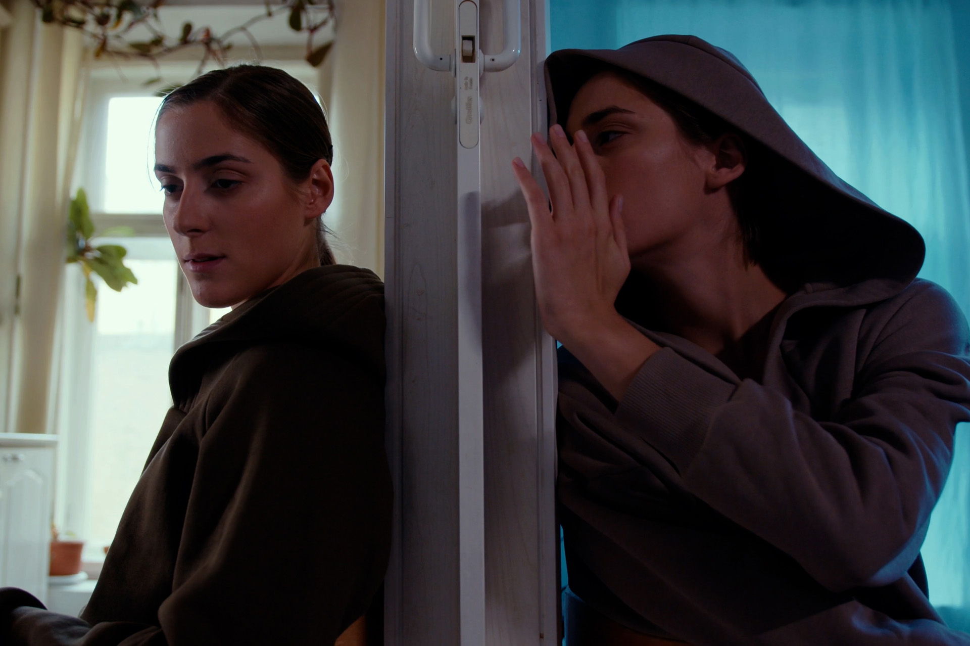 Twins in an apartment sitting on opposite sides of a door